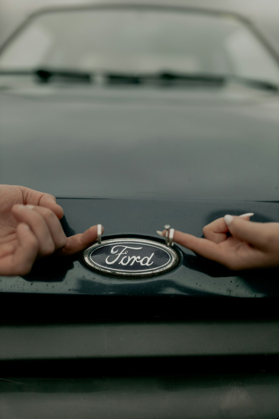 Hands holding car keys next to a parked sedan